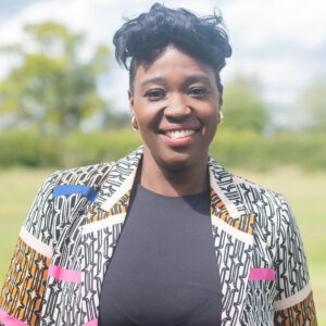 Corporate headshot, black female, black hair, brown eyes, suit, outside in colour